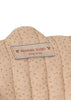 Close-up of a beige fabric tag with gold dots, stitched onto the quilted, removable fabric of the Konges Sloejd Tulle Doll Stroller - Rainbow Star. The label features “Konges Slojd, cherry on top” in red text alongside charming cherry graphics—seamlessly combining style and practicality for strollers with double wheels.