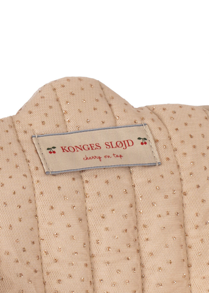 Close-up of a beige fabric tag with gold dots, stitched onto the quilted, removable fabric of the Konges Sloejd Tulle Doll Stroller - Rainbow Star. The label features “Konges Slojd, cherry on top” in red text alongside charming cherry graphics—seamlessly combining style and practicality for strollers with double wheels.