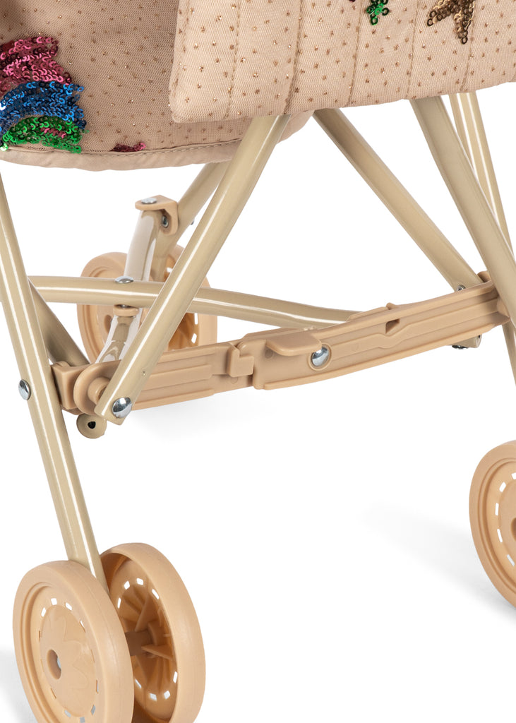 Close-up of the lower half of the Konges Sloejd Tulle Doll Stroller - Rainbow Star in beige, featuring double wheels and a fabric seat adorned with colorful rainbow star sequin designs.