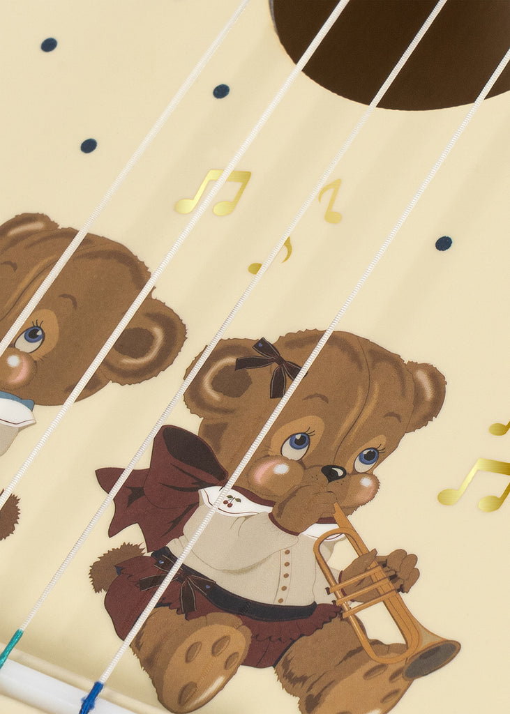 Illustration of a brown teddy bear playing a trumpet, surrounded by musical notes, with guitar strings and the Konges Sloejd Wooden Ukulele - Teddy Bear crossing over the image, highlighting the joy of exploring kids musical instruments.