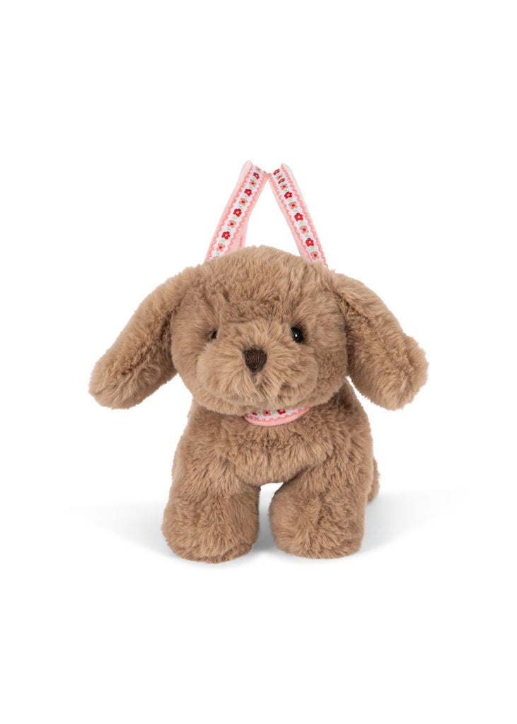 The Konges Sloejd Puppy Bag is a plush brown kids handbag with floppy ears, black eyes, and a pink patterned strap, shown standing upright against a white background.