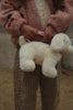A child dressed in a pink jacket and plaid pants carries the Konges Sloejd Puppy Bag - Off White by its leash.