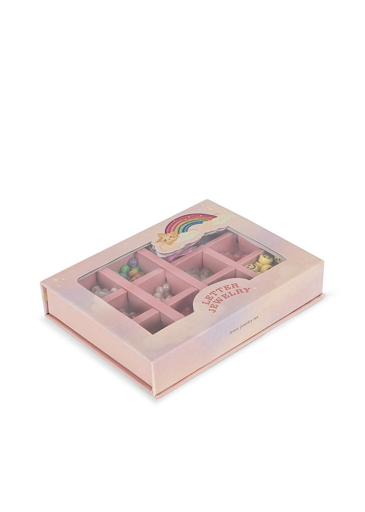 The Konges Sloejd ABC Jewelry Set is a pink bead box with a rainbow and unicorn lid, featuring colorful jewelry pieces and letter pearls, all neatly organized in separate compartments.