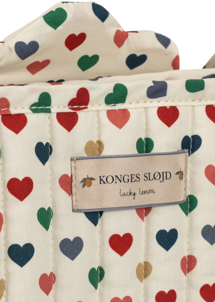 Close-up of a quilted cream fabric with colorful hearts, removable for washing, and labeled “Konges Sloejd Doll Stroller - Colored Hearts”—perfect for playtime adventures.