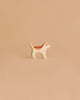 The Handmade Holzwald Golden Retriever Puppy, a small wooden dog figurine with brown and white details, stands on a smooth light brown surface against a beige background, highlighting the charm of sustainable toys.