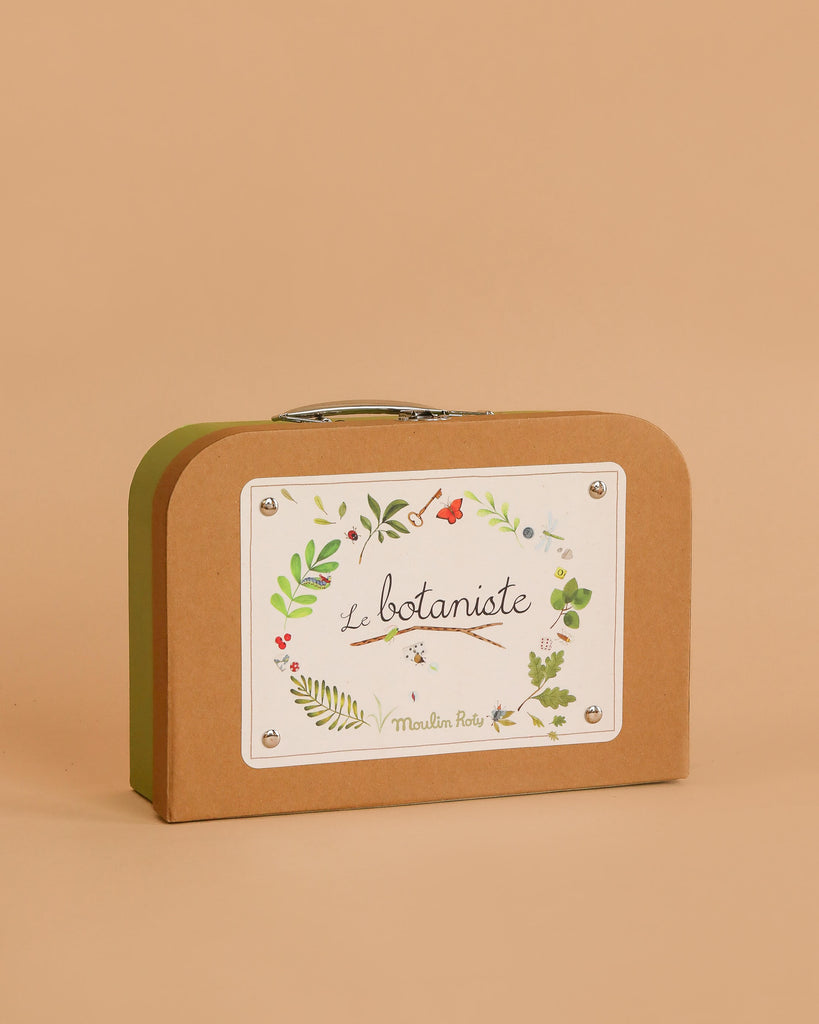The Moulin Roty Botanist Suitcase is a small brown case with a silver handle, labeled "Le botaniste" and decorated with leafy illustrations—ideal for young botanists or storing your budding garden collection.