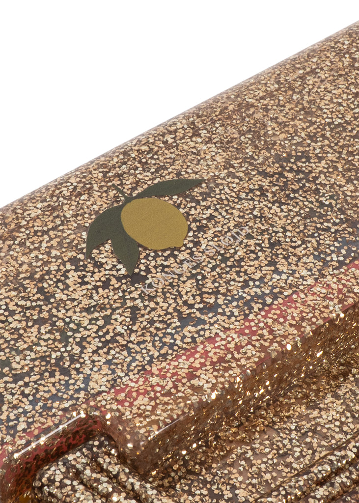 A close-up of the Konges Sloejd Creative Art Caddy - Tiger reveals a glittery, gold-speckled surface accented with a small, stylized green and yellow olive graphic, capturing the playful charm of children’s art supplies and making it a vibrant addition to any creative toolkit.