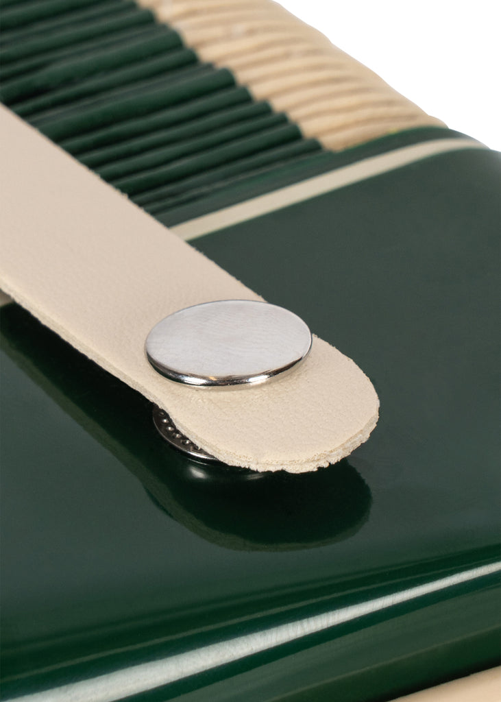 Close-up of a dark green Konges Sloejd Accordian featuring a cream-colored leather strap with a silver metal snap closure.