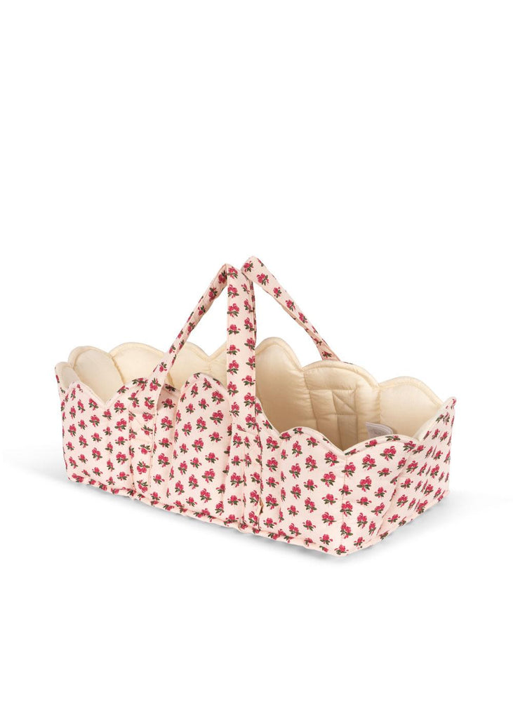The Konges Sloejd Doll Lift - Rosie Rose is a soft cotton carrier basket with scalloped edges, dual handles, and a cream base featuring red floral prints. It has a quilted cream interior and is made from OEKO-TEX certified materials.