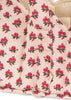 Close-up of quilted fabric on the Konges Sloejd Doll Lift - Rosie Rose, showing small red roses, green leaves, and a light pink background. Handle and stitching of this OEKO-TEX certified cotton doll carrier are visible.