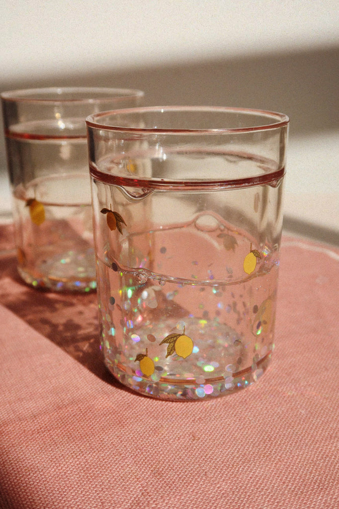 The Konges Sloejd Glitter Cups - Lemon (2 Pack) feature small lemon designs and iridescent glitter, adding a playful touch to kids’ drinkware.