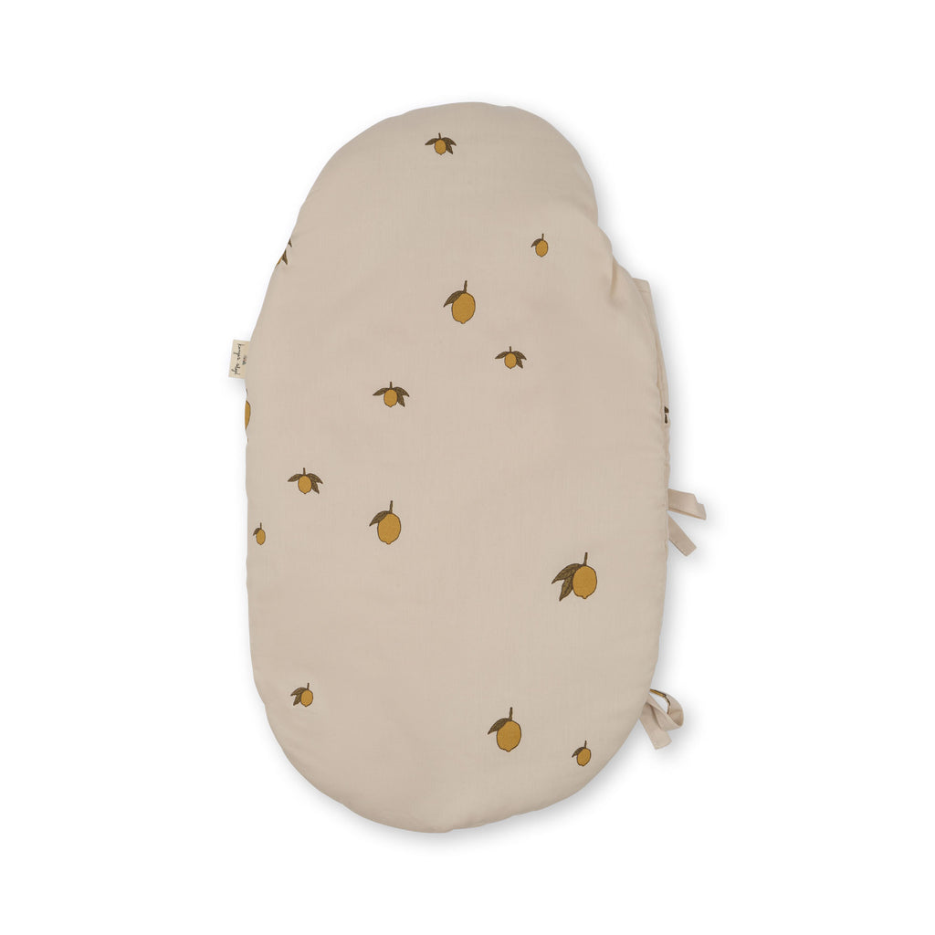 The Konges Sloejd Doll Sleeping Bag - Lemon features an oval shape, soft organic cotton fabric, and a beige cover adorned with small yellow lemons and green leaves, shown against a white background.