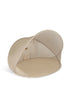 The Konges Sloejd Pop-Up Beach Tent UPF 50+ is a beige, dome-shaped, lightweight tent with a mesh side for outdoor use, offering UV protection, shade, and partial enclosure for relaxing at the beach or park.