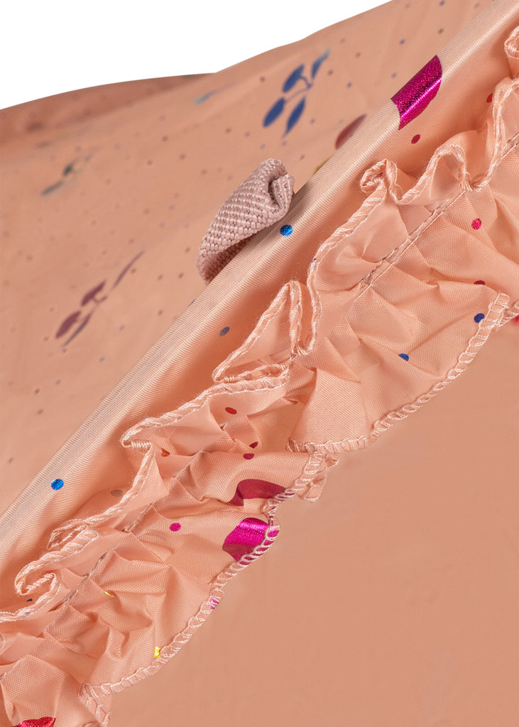 Close-up of the Konges Sloejd Lace Pop-Up Beach Tent UPF 50+ fabric in peach, featuring ruffled trim, detailed stitching, colorful confetti-like dots, and a visible fabric loop near the top edge.