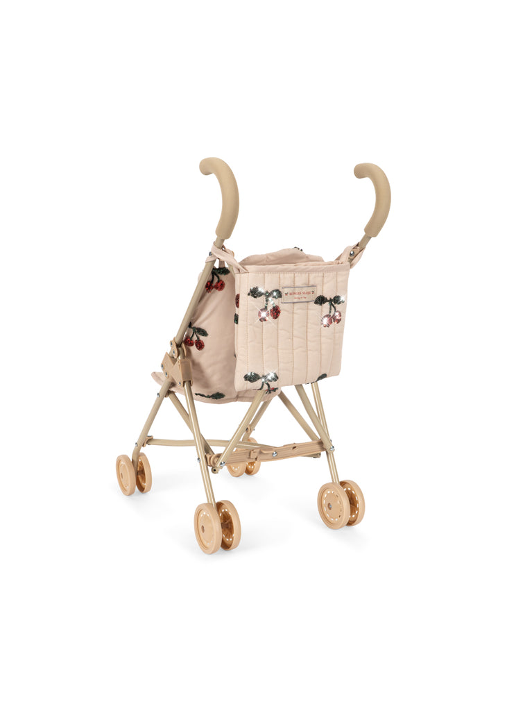 The Konges Sloejd Tulle Doll Stroller - Cherry Sequin is a compact, beige foldable stroller with quilted fabric, cherry sequin embroidery, double wheels, and curved handles, shown on a white background.