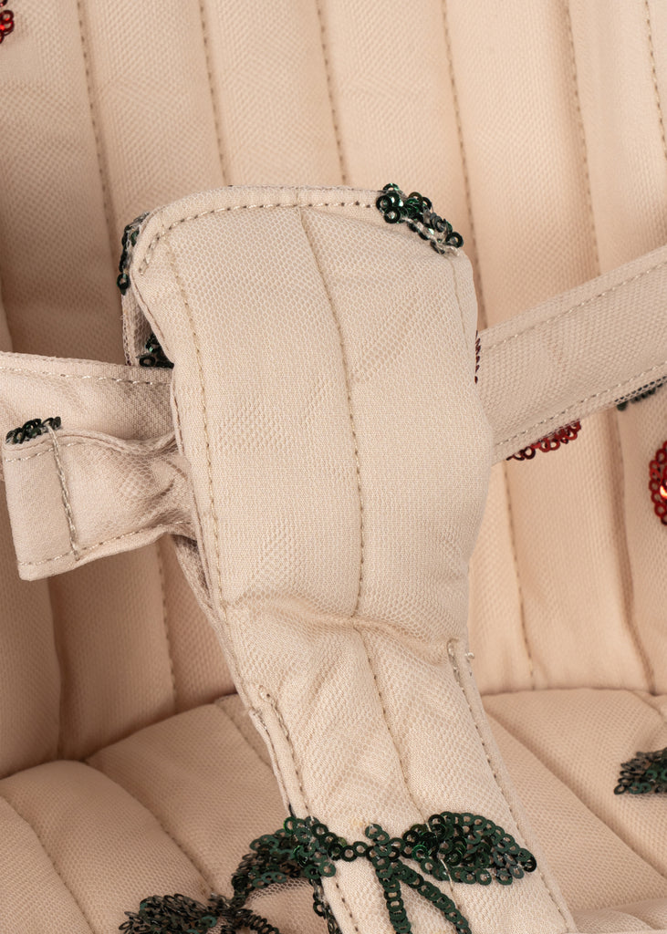Close-up of a beige padded strap with quilted stitching and green bead embroidery, featured on the Konges Sloejd Tulle Doll Stroller - Cherry Sequin.