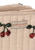 Close-up of the quilted beige fabric and red sequin-embroidered cherries on the Konges Sloejd Tulle Doll Stroller - Cherry Sequin, featuring a removable "KONGES SLOJD cherry on top" label.