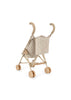 The Konges Sloejd Doll Stroller - Milk Tank is a beige stroller with curved handles and double wheels, featuring a fabric seat adorned with a tiny floral pattern.