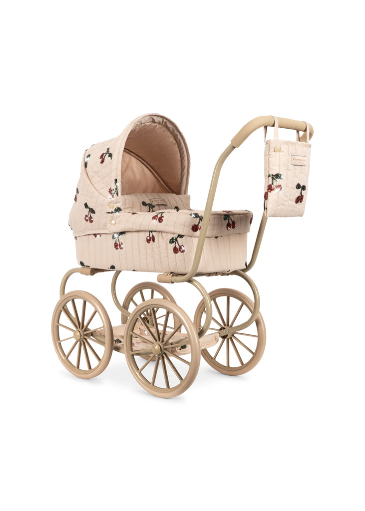 The Konges Sloejd Mini Tulle Doll Pram - Cherry Sequin is a vintage-style beige pram for children, featuring large wheels, a canopy, matching bag, and cheerful cherry sequin print fabric.
