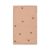 The Konges Sloejd Doll Nursery Set - Cherry Blush features a light brown organic cotton cloth napkin with a subtle checkered pattern and embroidered red cherries—ideal to pair with the matching organic cotton doll bib set.