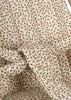 A close-up of the Konges Sloejd Doll Stroller - Milk Tank shows a padded fabric seat with a small pink and green floral print, featuring harness straps designed for secure seating.