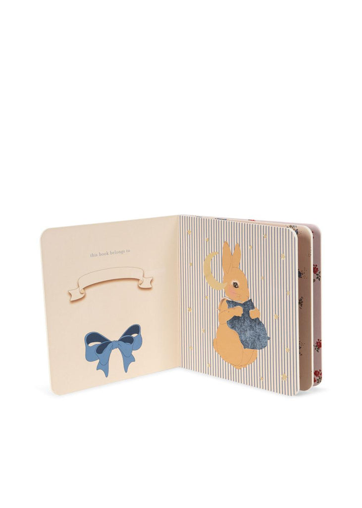 The Konges Sloejd Touch and Feel Book features a blue bow illustration on the left page and a rabbit in a blue jacket on the right, set against striped and floral backgrounds.
