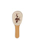 The Konges Sloejd Music Set - Circus features whimsical wooden instruments, including a painted hairbrush illustrated with a girl wielding a wand atop an elephant balancing on a red ball, all surrounded by gold stars—perfect for creative souls who adore imaginative circus-inspired designs and the charm of wood.