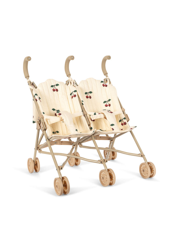 The Konges Sloejd Twin Doll Stroller - Cherry features a beige color, wooden wheels and handles, and cherry-patterned fabric seat covers, displayed against a white background.