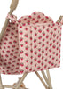 A close-up of a pink quilted bag with a red floral print, hanging from the handle of the Konges Sloejd Doll Stroller - Rosie Rose—a charming and practical addition to your doll accessories collection.
