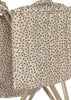 A close-up of the Konges Sloejd Doll Stroller - Milk Tank, featuring a cream fabric with a small brown and green floral pattern, draped over its light wooden legs and double wheels.
