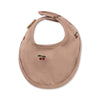The Konges Sloejd Doll Nursery Set - Cherry Blush includes a light brown organic cotton baby bib for dolls, featuring a snap closure and small embroidered red cherries with green leaves.