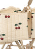 Close-up of the Konges Sloejd Twin Doll Stroller - Cherry, featuring beige quilted fabric with red cherry and green leaf prints, plus tan handles and wheels visible at the bottom.