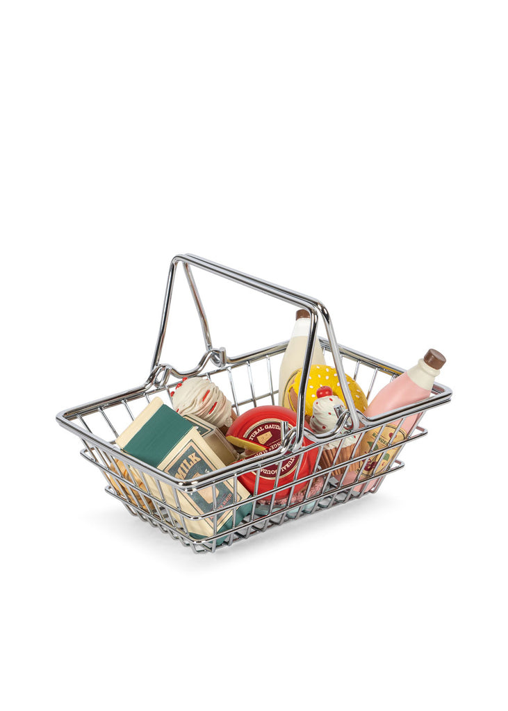 The Konges Sløjd Mini Market Grocery Set features a small metal shopping basket filled with miniature play food, including boxes, cans, bottles, and other tiny grocery items—perfect for imaginative mini market play.