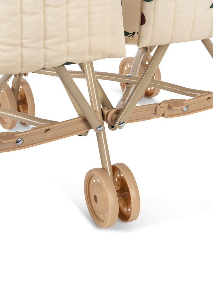 Close-up of the beige metal frame and peach-colored wheels of the Konges Sloejd Twin Doll Stroller - Cherry, with quilted fabric and cherry-patterned details partially visible at the top.