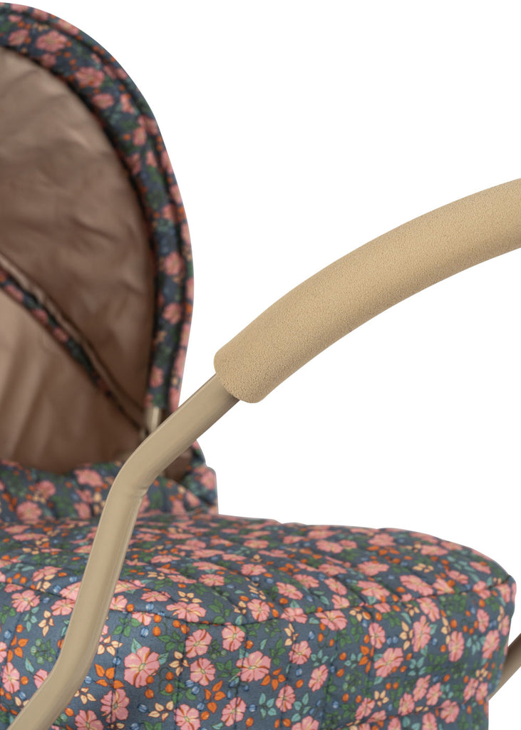 A close-up of the Konges Sloejd Doll Pram - Kyoto, featuring a beige handle, cozy padded mattress, and a floral fabric cover with pink and orange flowers plus green leaves on a dark background.
