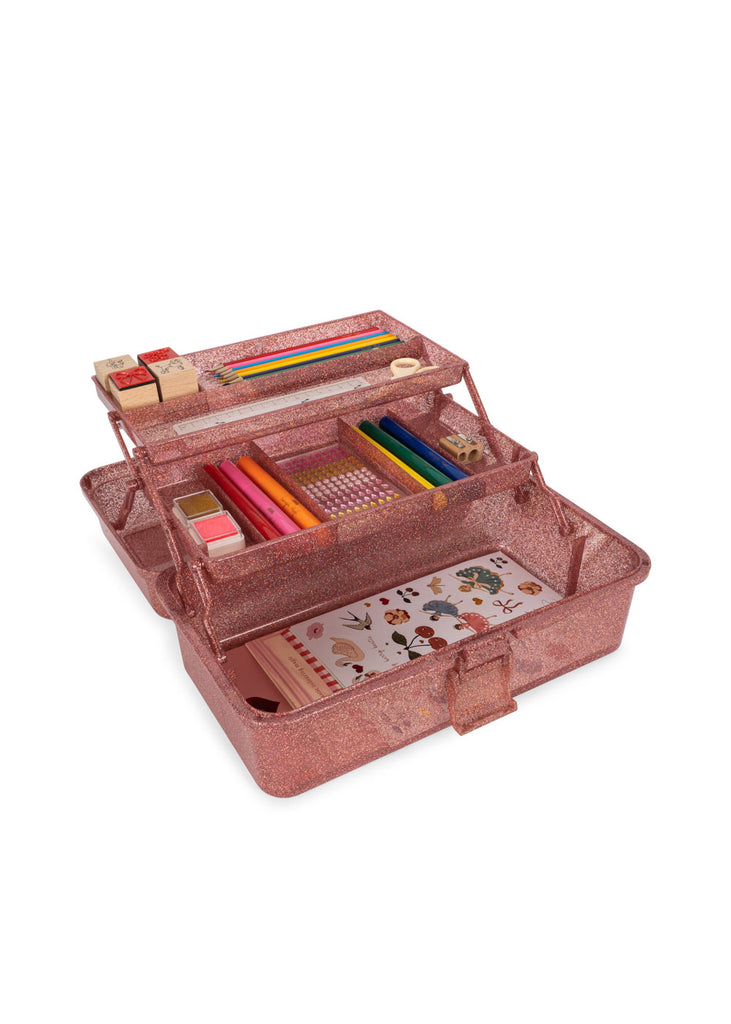The Konges Sloejd Creative Art Caddy - Glitter Rose is a pink, glittery organizer with compartments that neatly hold colored pencils, markers, stamps, stickers, a ruler, and an eraser—all easily visible when the lid is open.