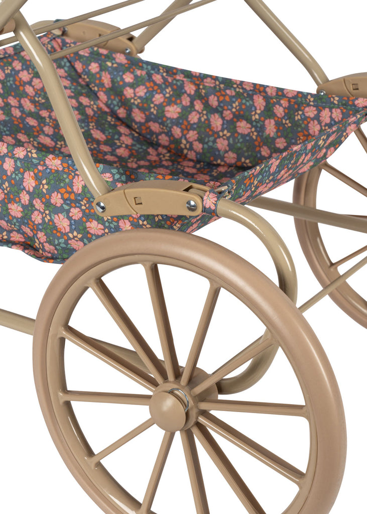 Close-up of the Konges Sloejd Doll Pram - Kyoto, featuring large beige wheels and a floral seat with pink and orange flowers on a dark background, plus a padded mattress for added comfort.