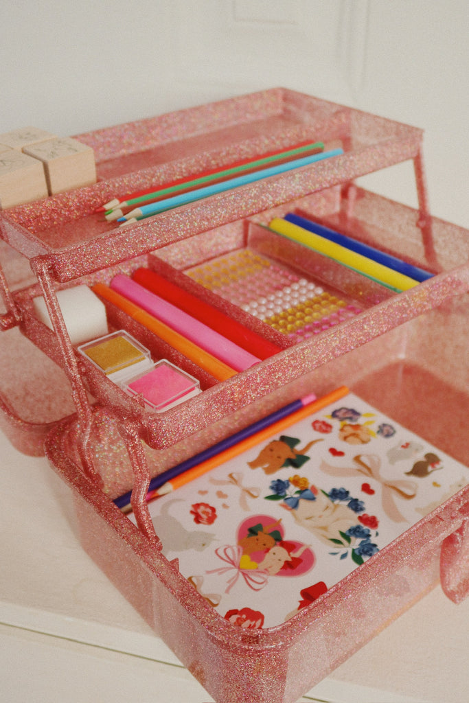 The Konges Sloejd Creative Art Caddy - Glitter Rose is a pink glittery organizer with three tiers, ideal for kids as an art kit or creative toolbox, and can neatly display pencils, pens, erasers, stickers, washi tapes, and colorful craft supplies.