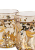The Konges Sloejd Glitter Cup - Let's Go Bananas features clear glass with illustrated bananas and gold, black, and silver confetti inside the walls—a playful cup ideal for any occasion.