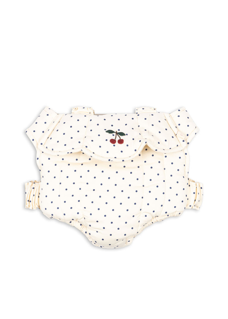 Pair the cream-colored baby diaper cover with navy blue polka dots, ruffled edges, and cherry embroidery with the Konges Sloejd Doll Carrier - Estate Dot for a charming playtime look your little one will love.