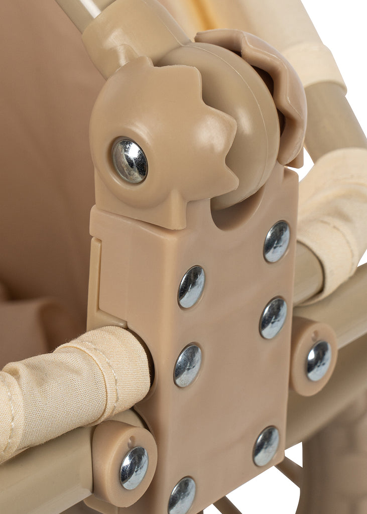 Close-up of a tan plastic hinge with metal screws, part of the folding mechanism, attached to beige fabric-covered bars of the Konges Sloejd Stoller Kids Wagon - Cherry.