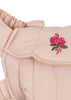 Close-up of the Konges Sloejd Doll Carrier in Cameo Rose, made from light pink cotton, with a ruffled strap and a flap embroidered with two pink flowers and green leaves.