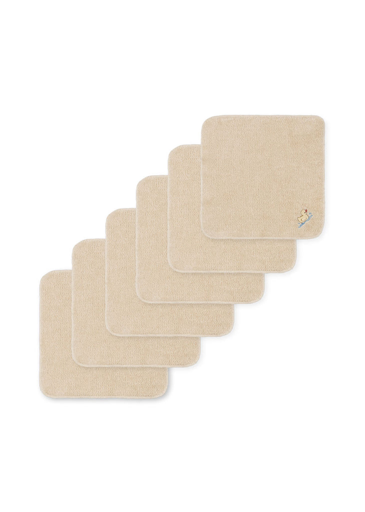 Six beige Konges Sloejd Organic Cotton Baby Cloths (6 Pack)—crafted from soft organic terry and ideal for little ones—are displayed in a staggered line. The front cloth is detailed with a small embroidered duck in the corner, making these perfect baby bath cloths for any nursery.