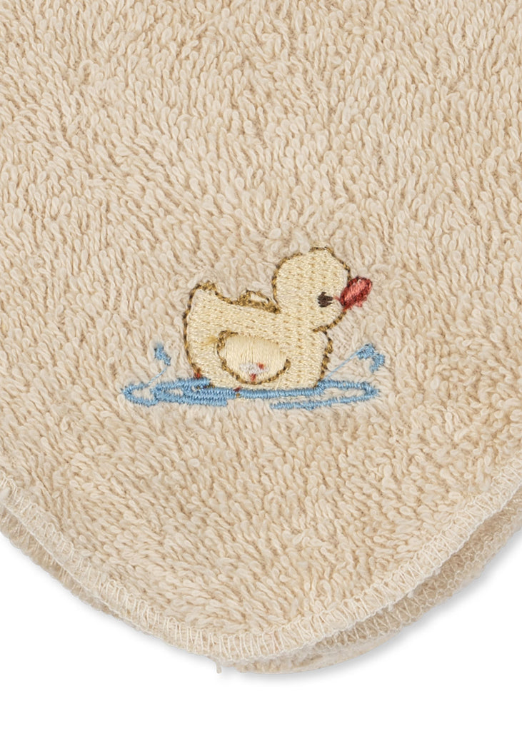 The Konges Sloejd Organic Cotton Baby Cloths (6 Pack) features soft beige terry cloths made from organic cotton, each adorned with a charming embroidered yellow duckling splashing water—outlined in brown with an orange beak. The embroidery is positioned near the rounded edge, making these cloths an adorable and practical addition to any nursery collection.