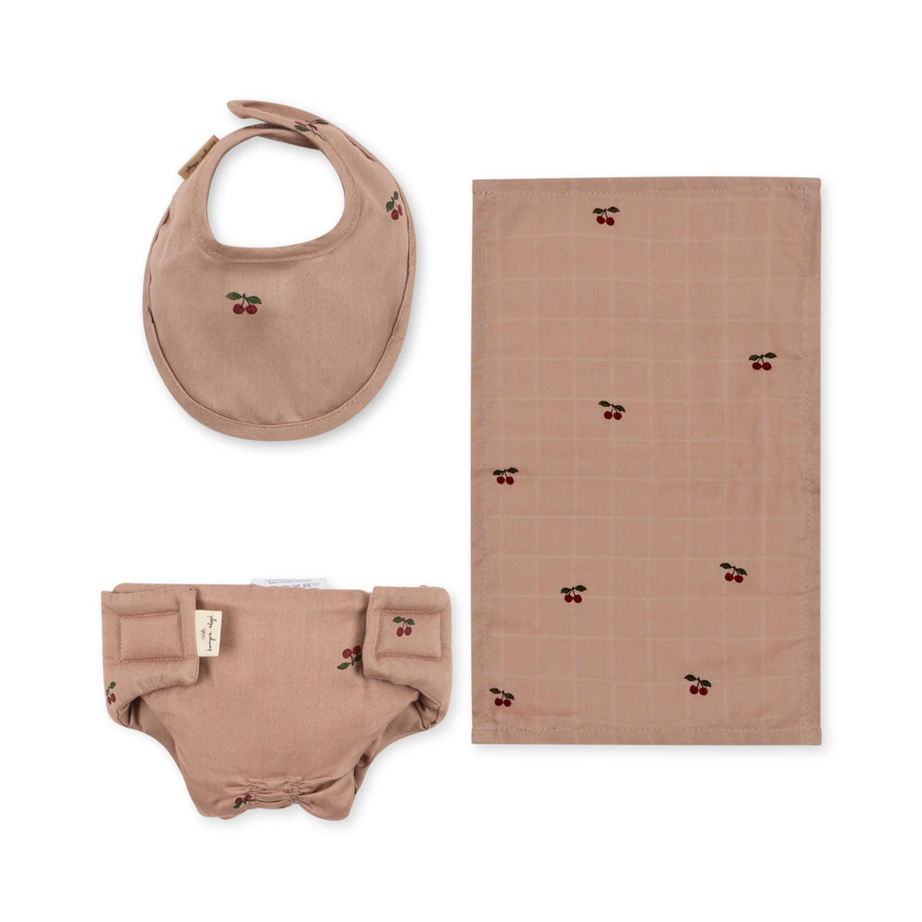 The Konges Sloejd Doll Nursery Set - Cherry Blush includes three brown organic cotton accessories with cherry prints: a bib, a burp cloth, and bloomers with bows—a charming doll accessory set.