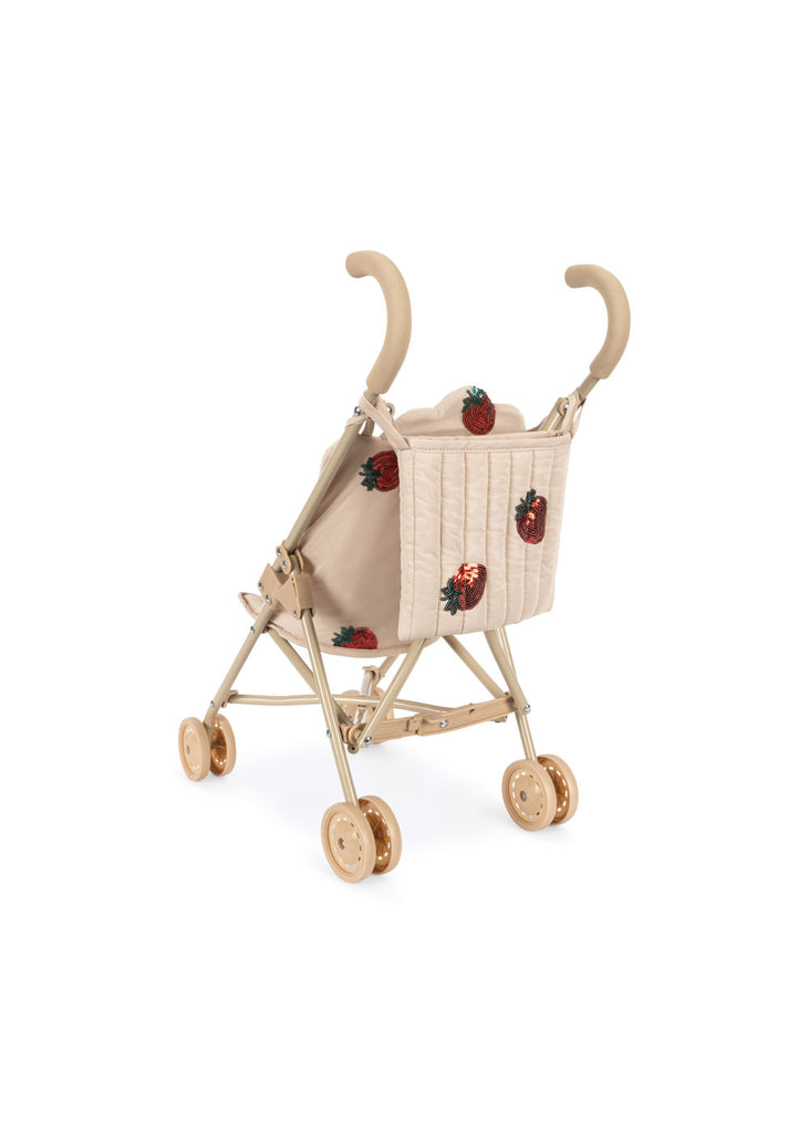 The Konges Sloejd Doll Stroller - Strawberry features curved handles, double wooden wheels, and a removable beige fabric seat with red strawberries, pictured against a white background.