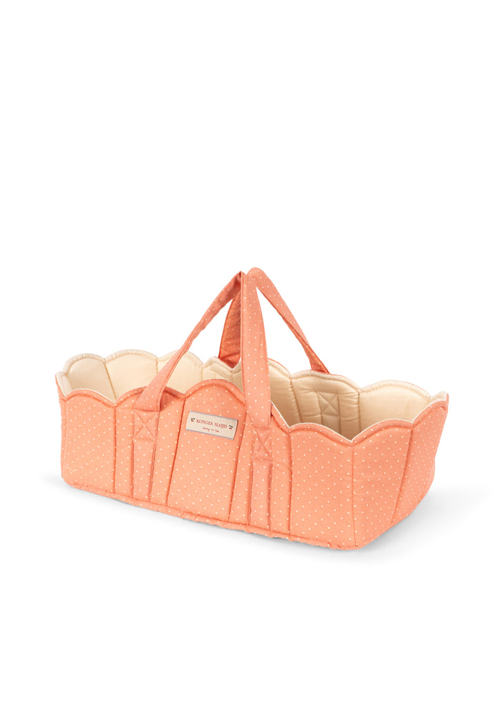 The Konges Sloejd Doll Lift - Rose Dot is a charming, peach-colored cotton doll carrier featuring white polka dots, scalloped edges, and a soft quilted interior. Designed with two handles for easy carrying and a cozy padded construction perfect for little hands, this OEKO-TEX certified Moses basket offers both safety and style for your child’s playtime.
