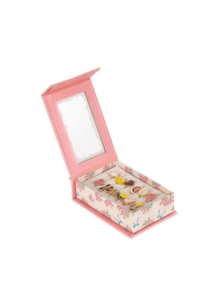 A pink, book-shaped box adorned with a floral pattern opens to reveal the Konges Sloejd 12 Pack Ring Set—an assortment of adjustable rings featuring playful decorative motifs, each displayed on a cushioned base. The inside lid features a scalloped-edged mirror, making it perfect for kids who love jewelry.