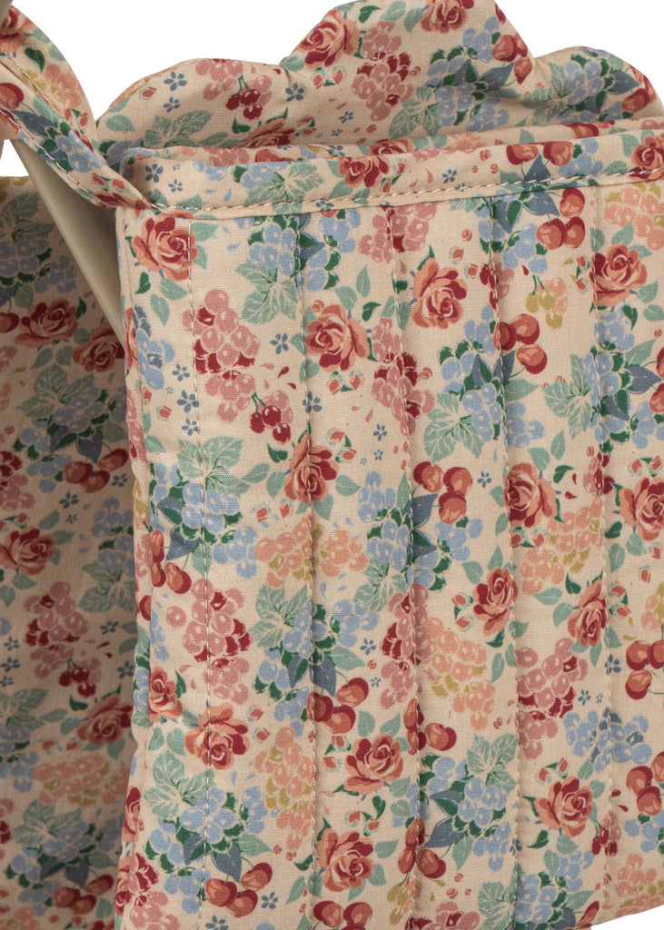 Close-up of the Konges Sloejd Doll Stroller - Vienna’s quilted fabric, featuring a red, blue, green, and pink floral pattern with vertical stitching and scalloped top edges—ideal for lining a carriage bag or doll stroller.