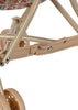 Close-up of the leg and wheel section of the Konges Sloejd Doll Stroller - Vienna, showing its beige frame, floral-patterned seat, double wheels, metal joints, plastic parts, and detailed wheel assembly.